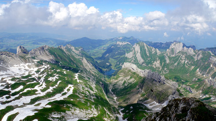 Fototapeta na wymiar Blick vom Säntis/ Bergwelt in der Schweiz; Blick vom Säntis auf das Alpstein-Massiv mit dem Seealpsee im Appenzellerland, steile Felsen und Schneefelder, 