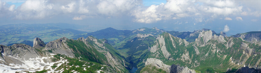 Fototapeta na wymiar Bergwelt in der Schweiz; Blick vom Säntis auf das Alpstein-Massiv mit dem Seealpsee im Appenzellerland, steile Felsen und Schneefelder, Panorama