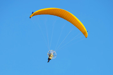 Flight on a motorized paraglider. Yellow paraglider with a paramotor.