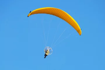 Fototapeten Flight on a motorized paraglider. Yellow paraglider with a paramotor. © nskyr2