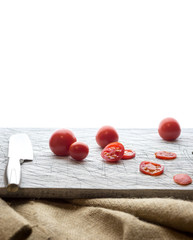 Small red cherry tomatoes spill out of on  old wooden table in r