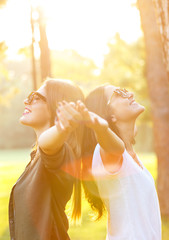 Two beautiful young woman expressing freedom outdoors with her arms outstretched.