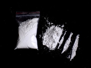 Cocaine drug powder in bag and cocaine powder pile and lines on black background
