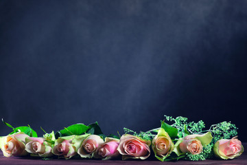 Rose flowers are on the table on an abstract dark background. Space for text or image