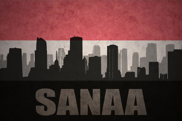 Fototapeta premium abstract silhouette of the city with text Sanaa at the vintage yemen flag background