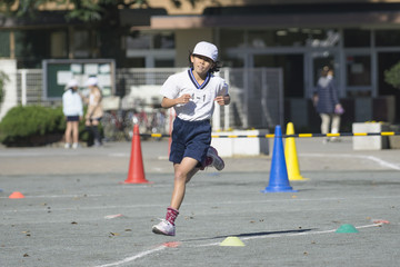 Young girl running in race at elementary school sports day
