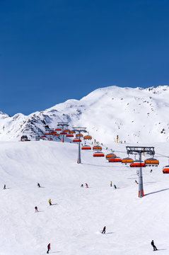 Skiers and orange chairlift in Alpine ski resort in Solden in Otztal Alps, Tirol, Austria