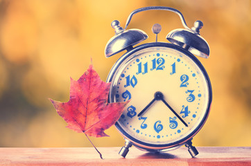 Vintage alarm clock on autumn season background