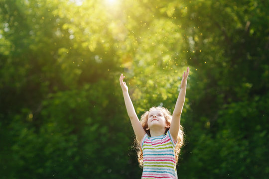 Cute little girl stretches her hand to catch sun rays.