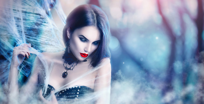 Fantasy Halloween woman portrait. Beauty sexy vampire posing, wearing spider web
