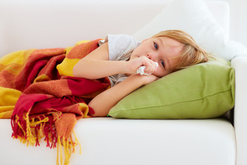 sick kid with runny nose and fever heat lying on couch at home © Olesia Bilkei