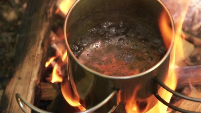 Water boiling in a pot. Water boils in the iron circle. Hiking circle at the stake. Burning firewood. Close-up. View from above. The sound of the crackling fire and firewood. FullHD.