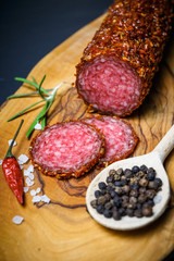 dried salami crusted in ground red pepper on dark background