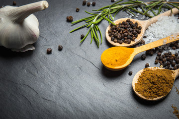 spices and herbs over black stone background, top view with copy space