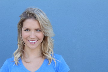 Woman portrait with beautiful blond hair smiling and laughing - isolated over a blue background...