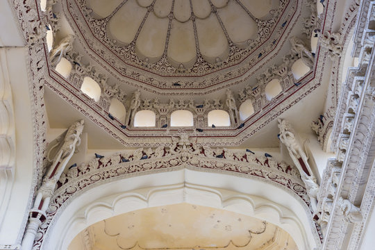 Madurai, India - October 21, 2013: Shot on the abundant decoration of one dome and the supporting columns and bow at Nayak Palace. White with wine-colored images. Pigeons.