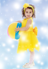Little girl in yellow dress holding a ball