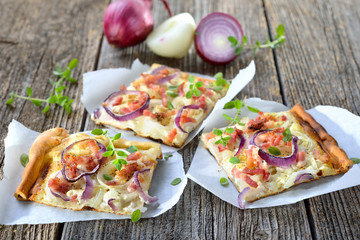 Streetfood: Klassische Elsässer Flammkuchen-Schnitten mit Zwiebeln und Speck auf Butterbrotpapier serviert - Hot baked tarte flambee from Alsace with onions, bacon and sour cream ready to eat