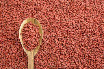 Annatto seeds in wooden spoon - Bixa orellana