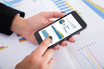 Businesswoman Analyzing Financial Graphs Using Smartphone