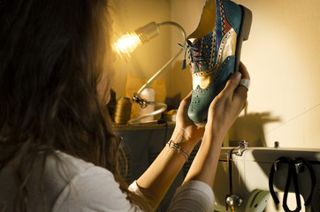 Fototapeta na wymiar Female, designer shoemaker looking at her work