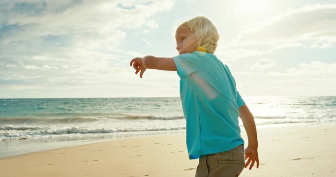 Young boy playing football on the beach at sunset in slow motion