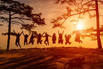 Asians traveler jumping in happy time at Phu Kradueng National Park at Sunset in Loei Province of thailand