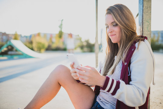 Cute blonde girl using a phone in the street