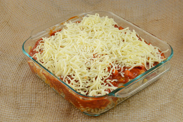 Unbaked prepared casserole dish with turkey, mixed vegetables, pasta, marinara sauce and shredded mozzarella cheese