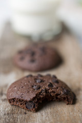 Chocolate chip cookies and glass of milk on wooden plate