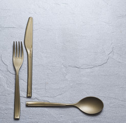 Fork, knife and spoon on the stone plate with copy space.