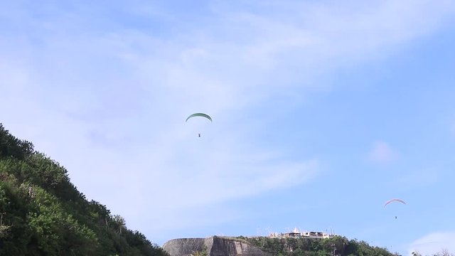 Paragliders fly over amazing mountain near the beach, Bali island, Indonesia. Beautiful view, sky and mountain full of plants. Full HD, 50 fps, 1080p.