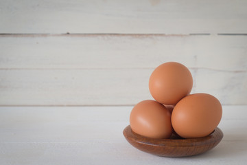 Egg in a wooden bowl on wooden table white. Chicken Egg. Top view with copy space