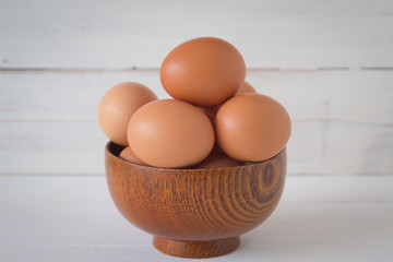 Egg in a wooden bowl on wooden table white. Chicken Egg. Top view with copy space