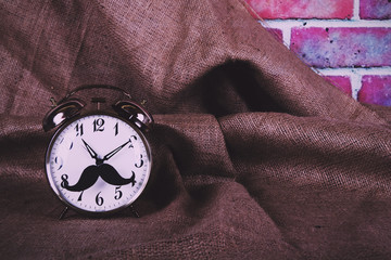 Alarm clock with a black hipster mustache Vintage Retro Filter.