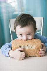 Boy bites bread. Cheeked little boy chewing on bread with a mischievous kind