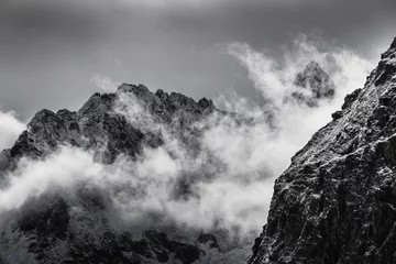 Gartenposter Schwarz-Weiß-Foto von schneebedeckten felsigen Berggipfeln mit Nebel © EdNurg
