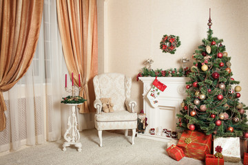 Cozy living room in holiday time. Christmas tree with cones, balls, Garland standing near fireplace, lot of presents under it. On the one wall hangs a needles wreath on the other is watches over sofa