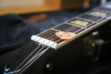 Fototapeta premium Acoustic guitar with piectrum close up in dark background