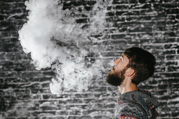 Young man with beard vaping an electronic cigarette. Vaper hipster smoke vaporizer.