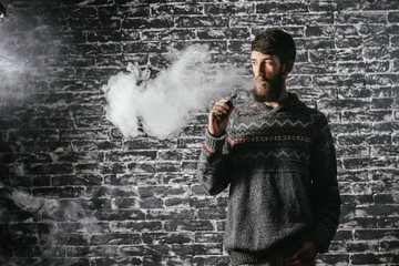 Young man with beard vaping an electronic cigarette. Vaper hipster smoke vaporizer.