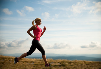 runner - woman runs cros country on a path in early autumn