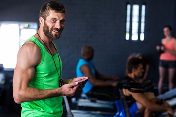 Portrait of smiling hipster holding tablet in gym