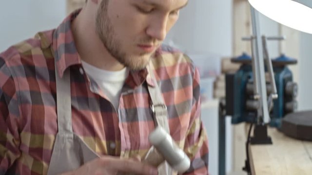 Jeweler shaping the ring with hammer on mandrel in workshop