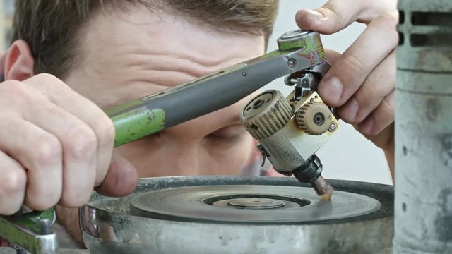 Closeup of jeweler preparing diamond held by dop for polishing it on faceting machine