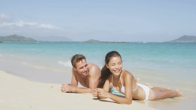 Beach vacations suntan couple relaxing in Lanikai, Oahu, Hawaii, USA. Blue sky copy space background for holiday vacation travel concept.