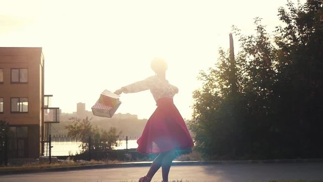 Shopaholic joyful woman in beautiful dress holding many shopping bags walking on the street through the sun during sunset in slowmotion. 1920x1080