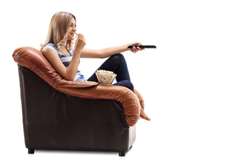 Woman changing channels on TV and eating popcorn