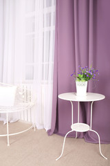 White table with flower in the room on background of purple curtains