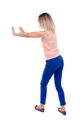 back view of woman pushes wall.  Isolated over white background. Rear view people collection. backside view of person. The blonde in a pink t-shirt shoves his hands in the side.